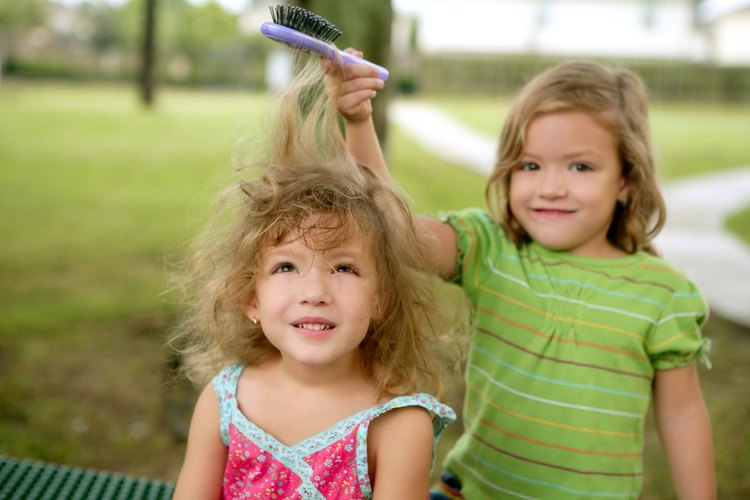 Niña cepillando el cabello de su hermana pequeña.