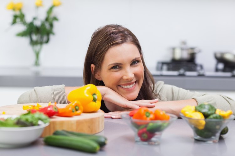 Una mujer sonriendo detrás de pimientos.