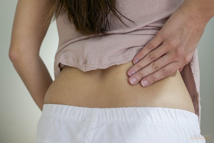 Un primer plano de una mujer que frota su parte lumbar.