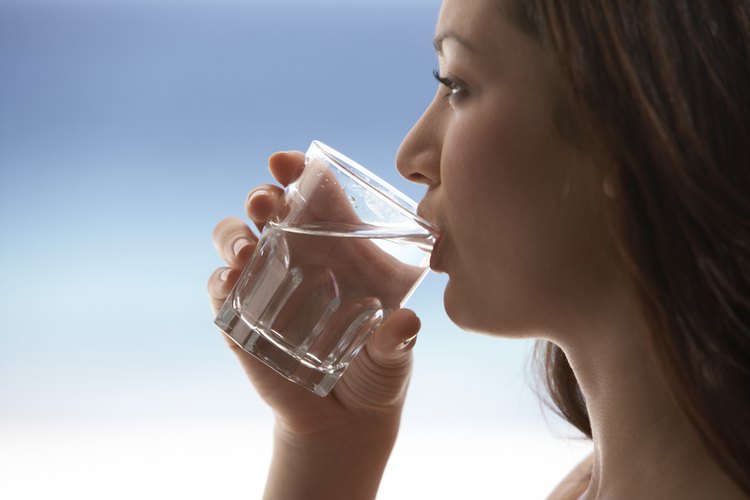 Una mujer bebe un vaso de agua.