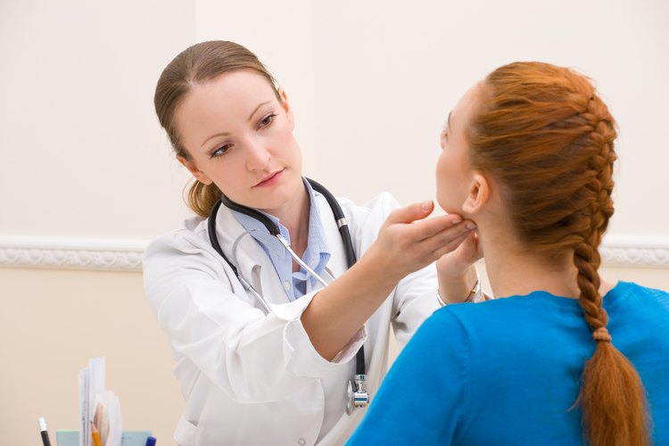Una médico examinando la tiroides de una mujer.
