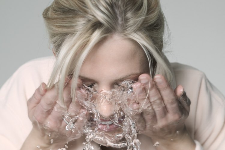 Una mujer salpica agua en su rostro.