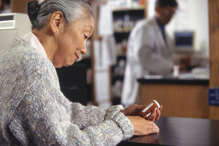 Una mujer leyendo la etiqueta en la botella de medicación.
