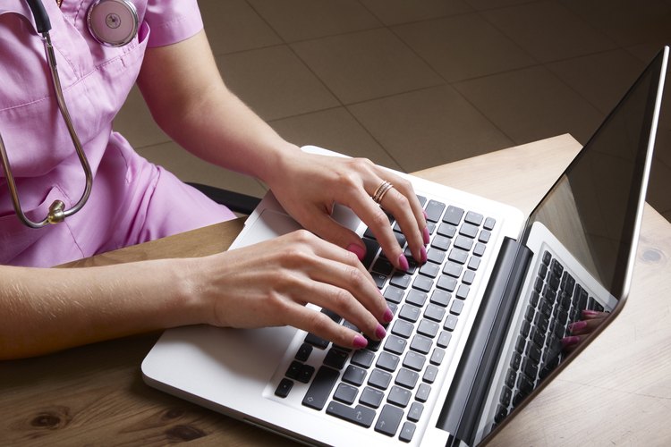 Un trabajador médico introduce datos en su computadora en un escritorio.