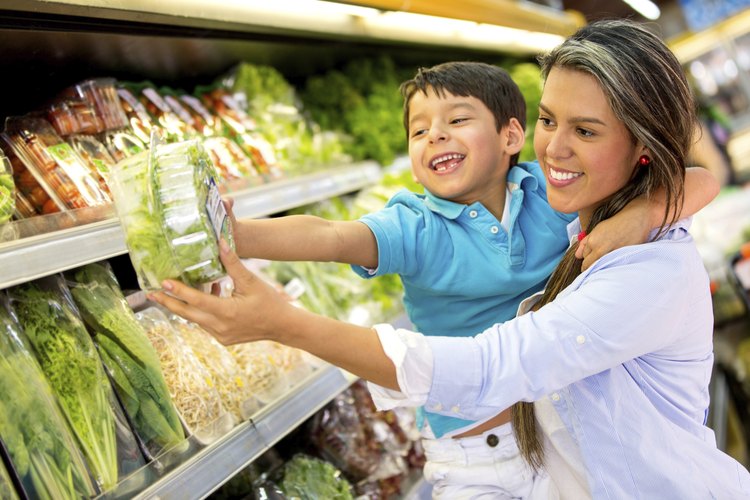 Mujer eligiendo vegetales con su hijo.
