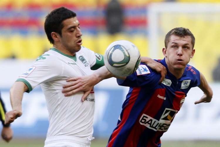 Jugadores de la liga de fútbol ruso intentan empujarse entre sí fuera del camino para conseguir el balón.
