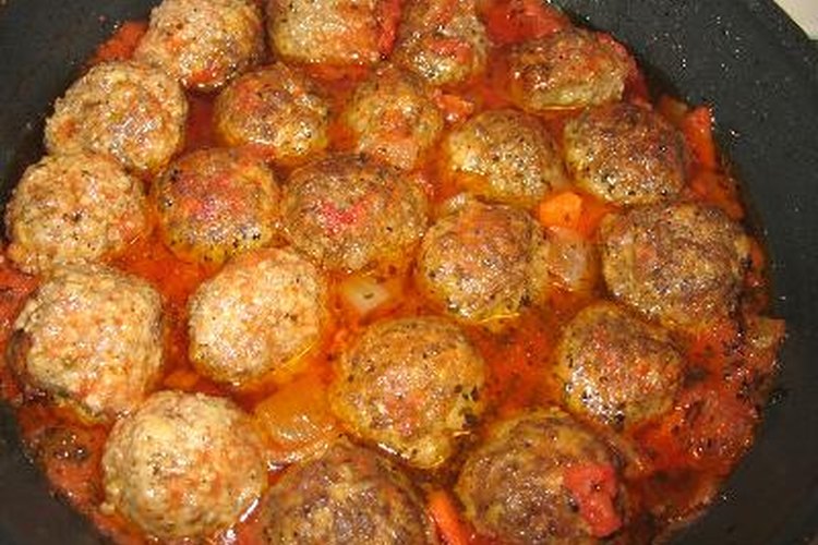 Cocina a fuego lento cocinando albóndigas en salsa de espaguetis para mejorar su sabor.