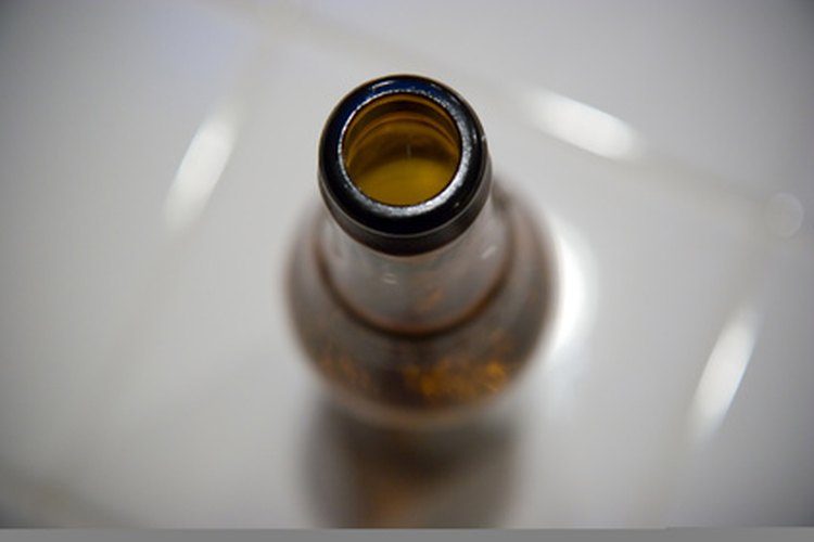 Una botella de cerveza necesita ser limpiada por una lavadora de botellas mediante un chorro de agua.