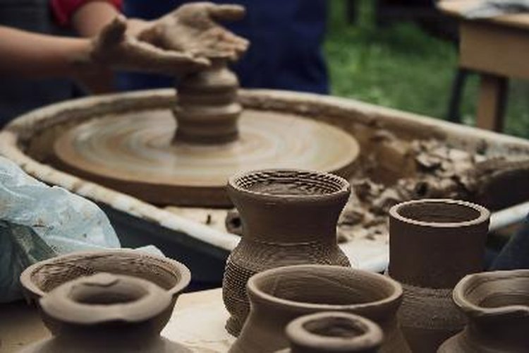 Coloca el trozo de arcilla en el centro de la rueda de cerámica y moldea el montículo a la forma deseada.