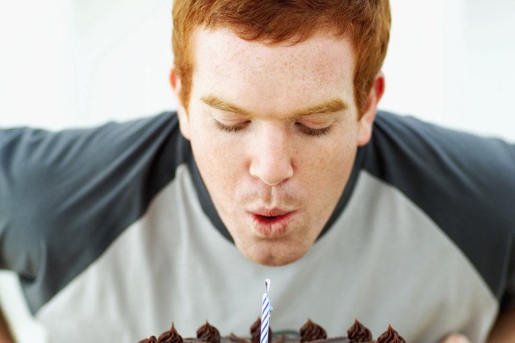 Hombre apagando las velas de su pastel de cumpleaños.