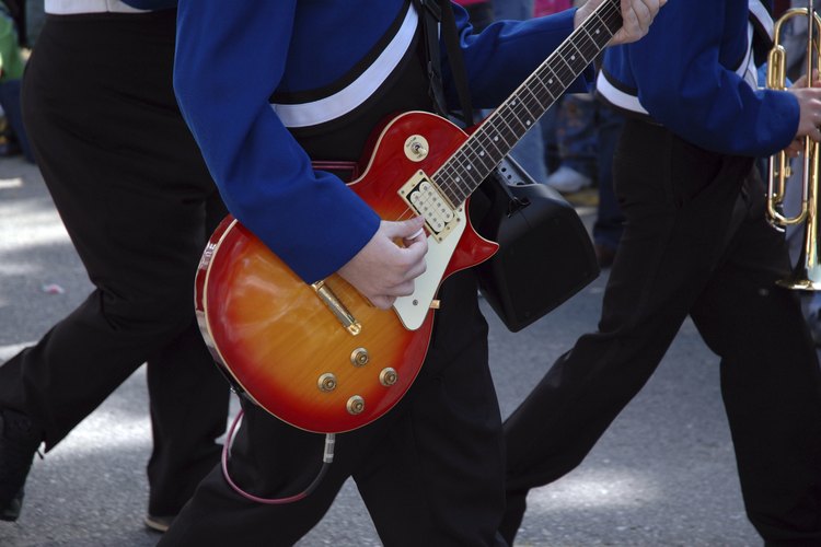 Estudiante en uniforme con una guitarra para la práctica de la banda.