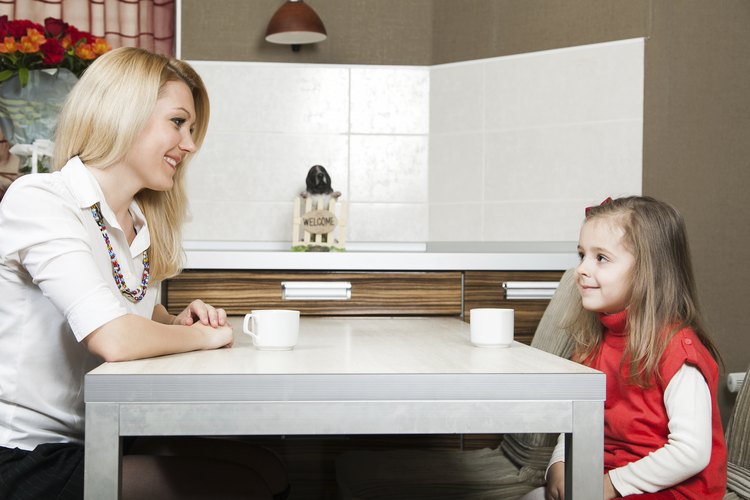 Madre joven y su hija hablando en una mesa.