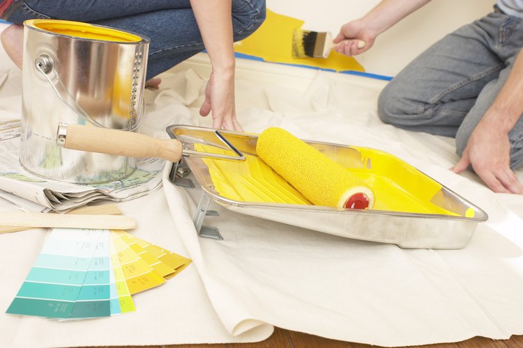 Mujer colocando la herramienta de pintura en la pintura.