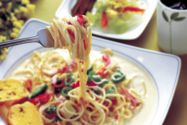 Una salsa de parmesano cubre pasta primavera.