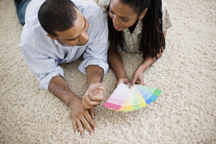 Una pareja ve muestras de pintura en la alfombra.