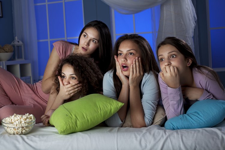 Adolescentes viendo una película con palomitas de maíz.