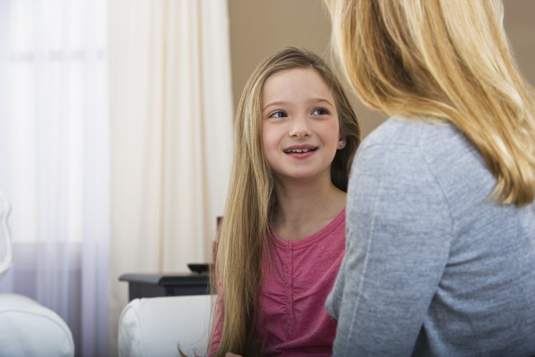 Una niña sonrie mientras escucha a su madre.