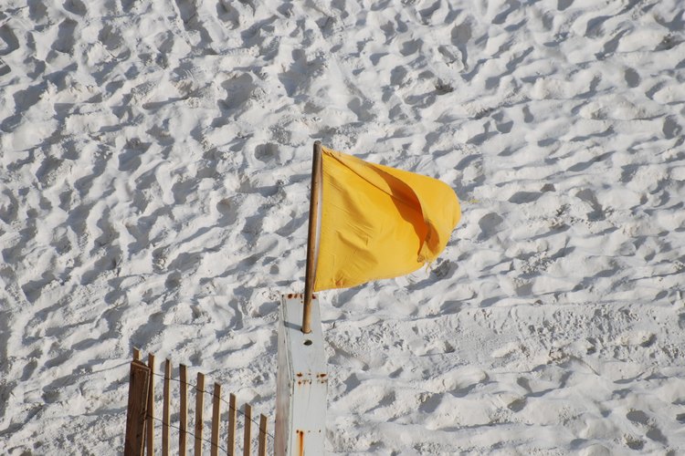 Una bandera de advertencia amarilla en la arena.
