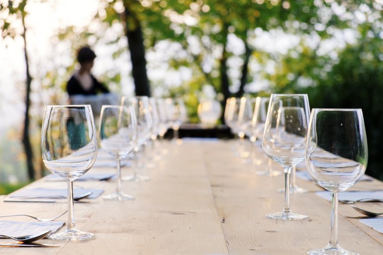 Copas vacías de agua y vino en una mesa al aire libre.