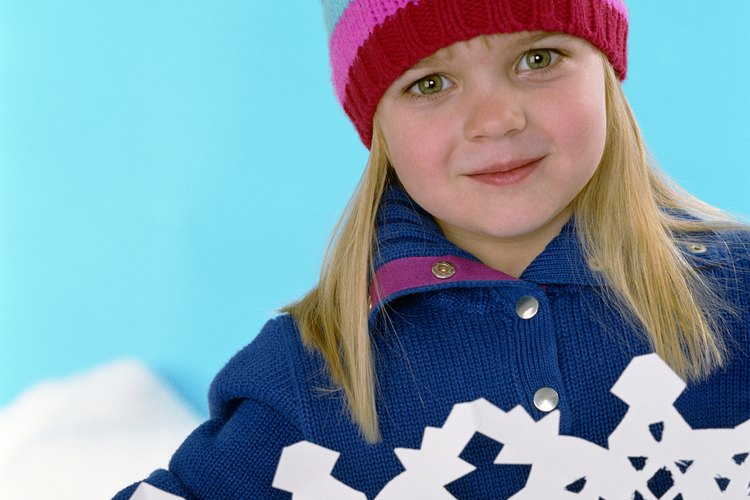 Dobla papel blanco y haz que tu niño recorte patrones de encaje en forma de copos de nieve.