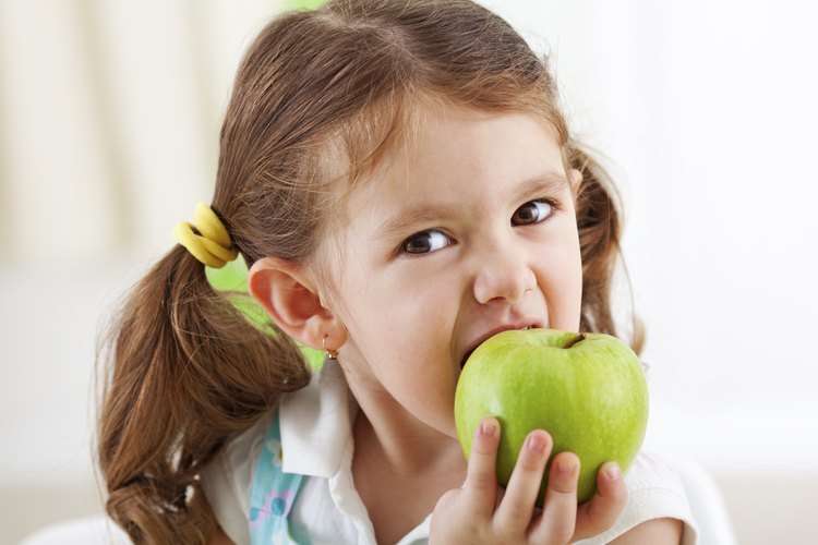 Niña mordiendo una manzana.
