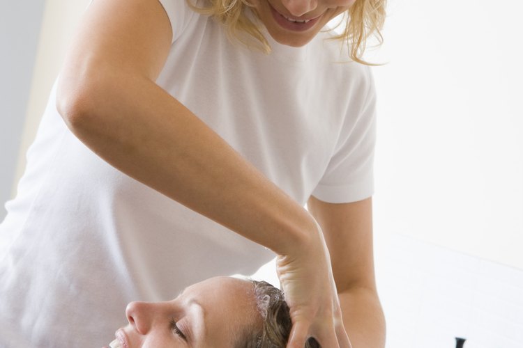 Un estilista lavándole el cabello a un cliente.