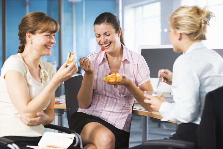 Mujer comiento fruta en la oficina.