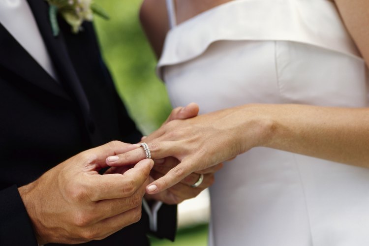 Novio colocando el anillo de bodas en el dedo de su novia.
