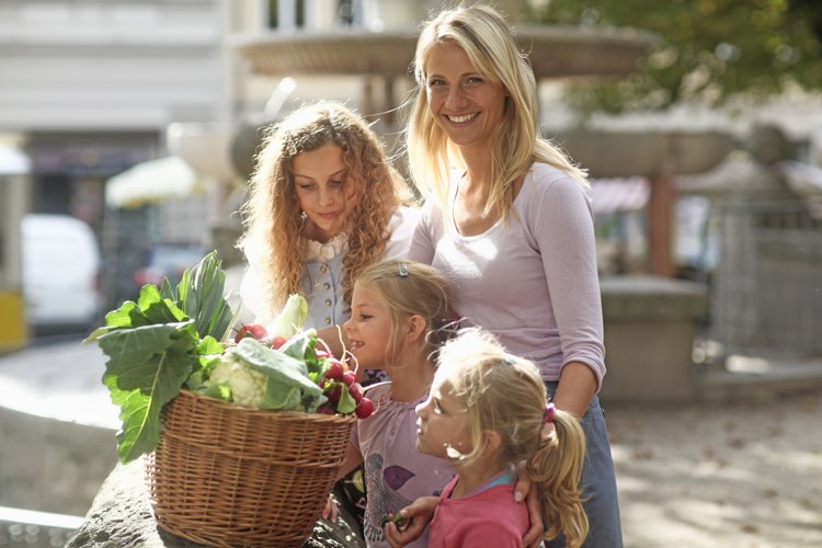 Madre comprando alimentos orgánicos con sus tres hijas.