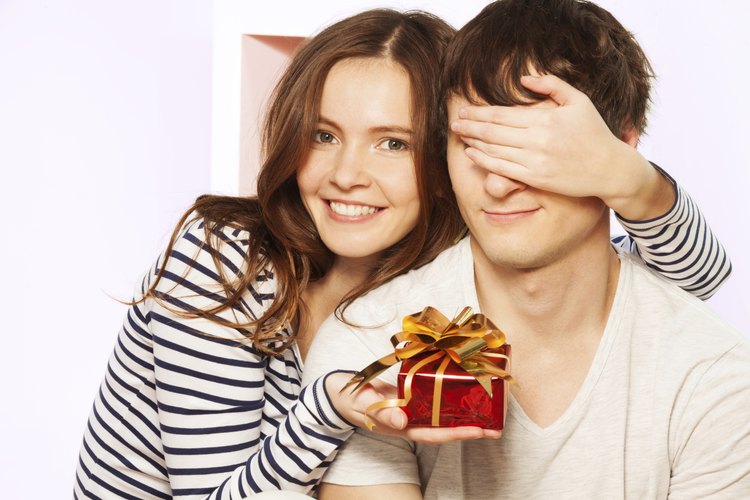 Chica sosteniendo un regalo para un hombre joven.
