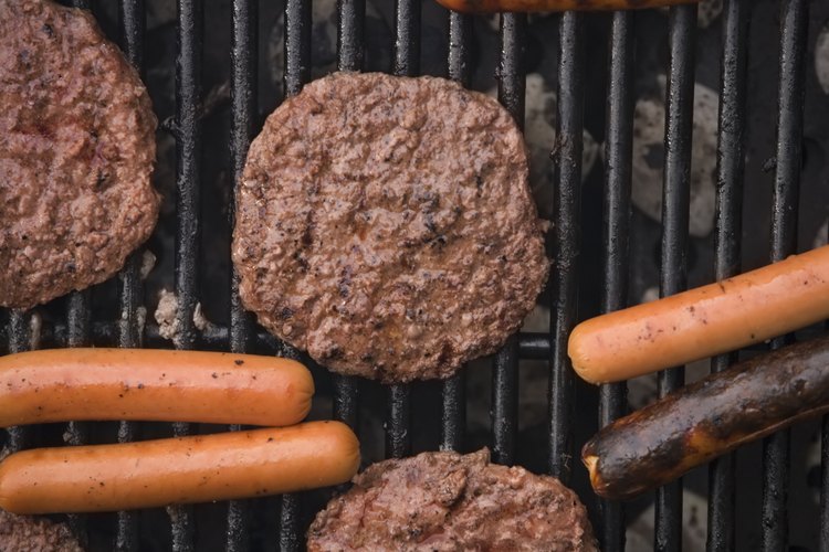 Hamburguesas y perros calientes en una parrilla.