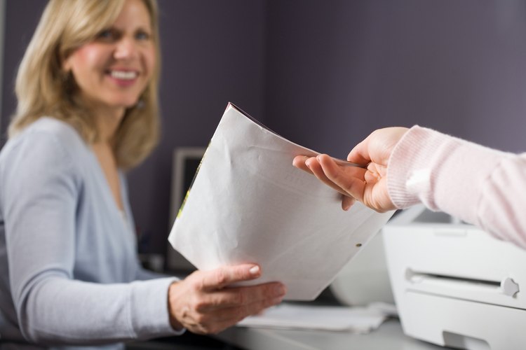 Una secretaria técnica realiza tareas de rutina que involucran documentación de informes y entrada de datos.