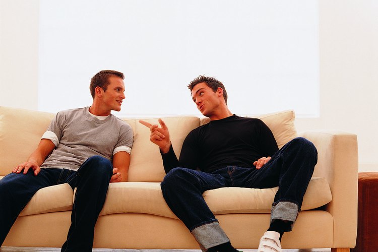 Dos hombres conversando en un sillón.