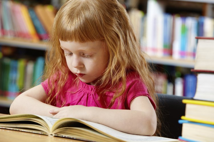 Una pequeña niña leyendo en la biblioteca.