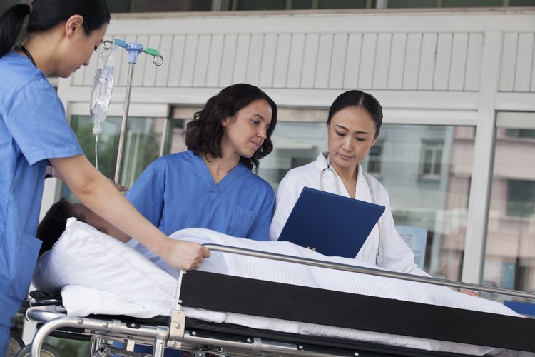 Médicos leen una planilla mientras ingresan a un paciente