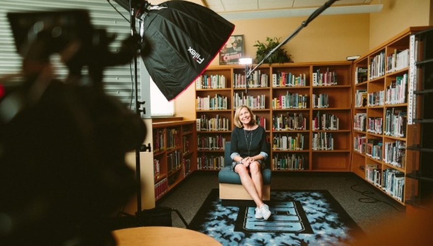 Woman sitting on armless chair with light between bookcases in room.jpg
