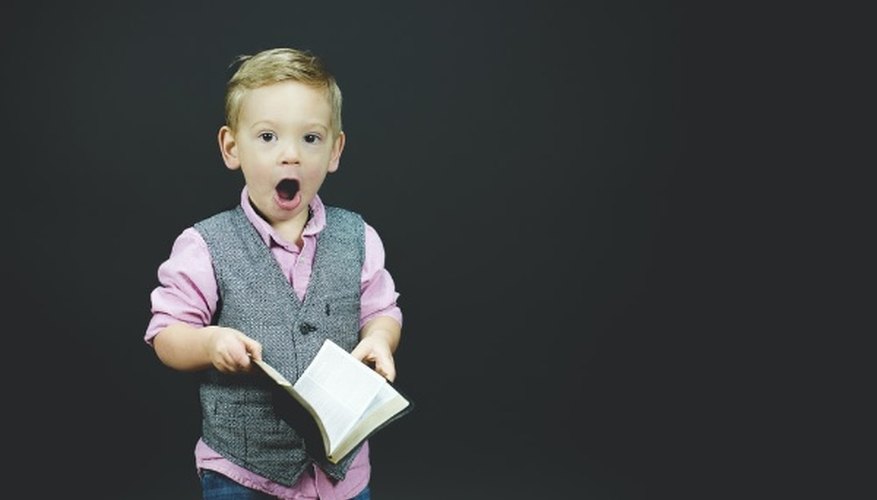 Boy wearing gray vest and pink dress shirt holding book.jpg