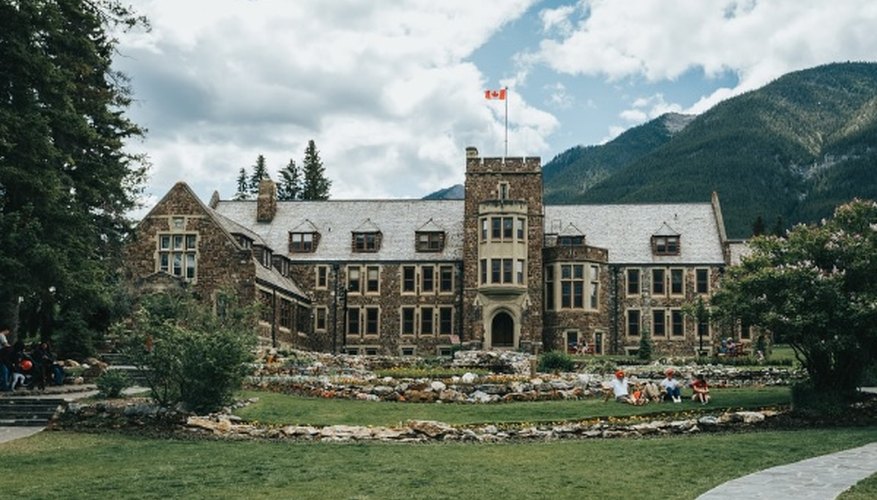 Brown concrete building near green grass field and mountain under white clouds and blue sky during.jpg