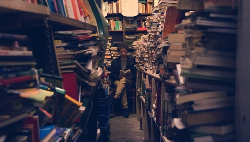 Man sitting reading book on the end of pile of book racks.jpg