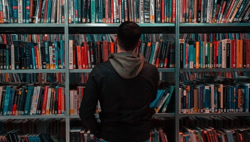 Person wearing black and gray jacket in front of bookshelf.jpg