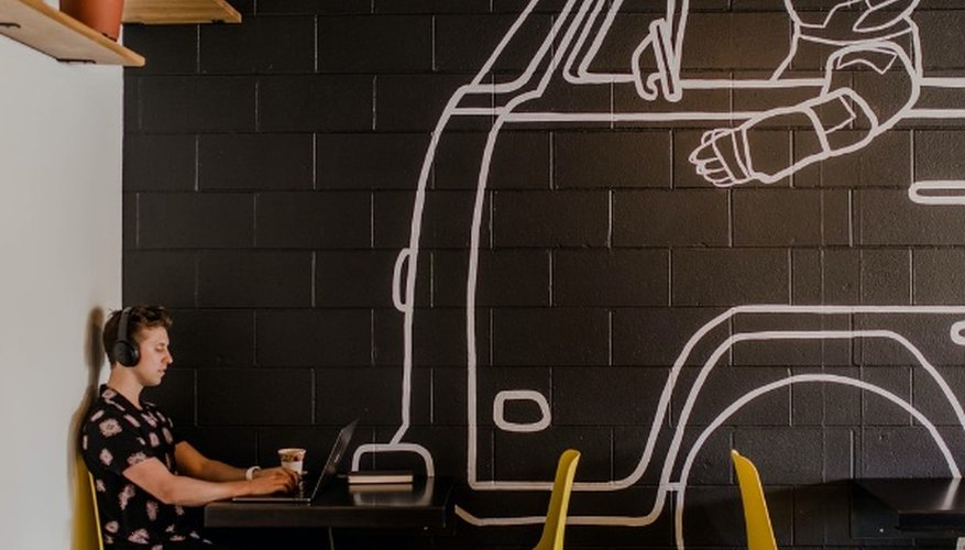 Man wearing headphone using laptop while sitting beside table inside cafe.jpg
