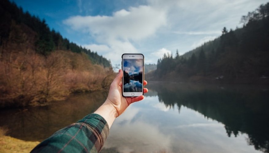 Person holding iphone while taking picture of mountains and body of water during daytime.jpg