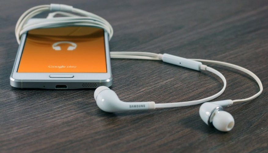 White samsung android smartphone turned beside white earbuds on brown board.jpg