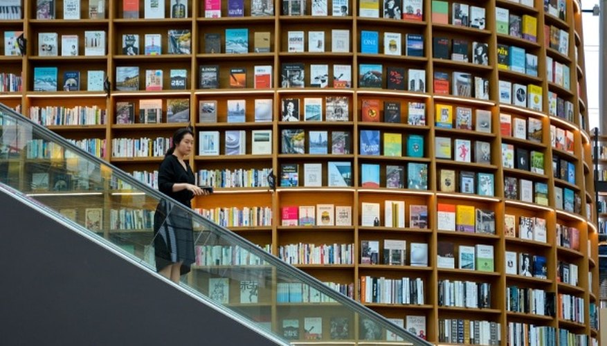 Woman standing on escalator near brown wooden book shelves.jpg