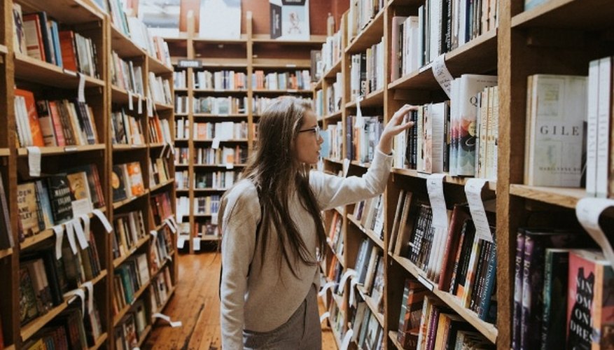 Woman holding book on bookshelves.jpg