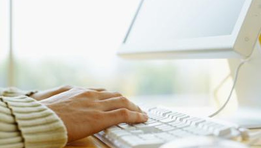 Close-up of woman typing on a desktop computer.