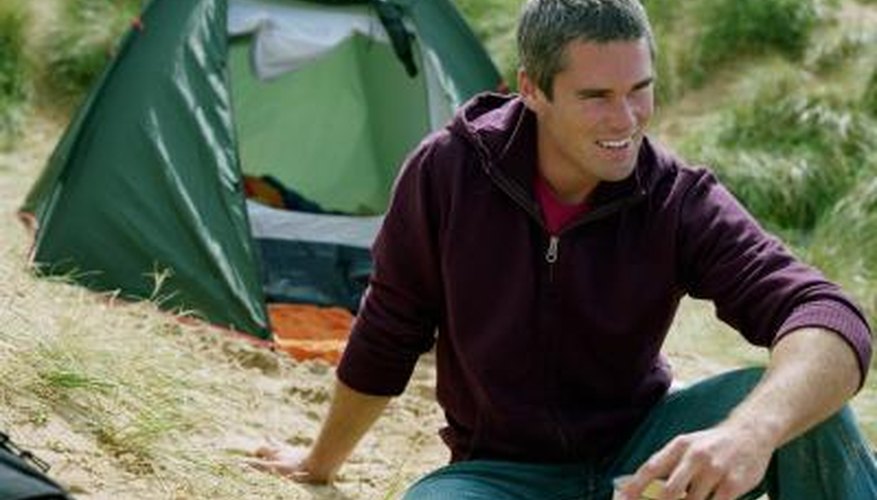 Photo Credit: Digital Vision/Digital Vision/Getty Images Man relaxing outside tent