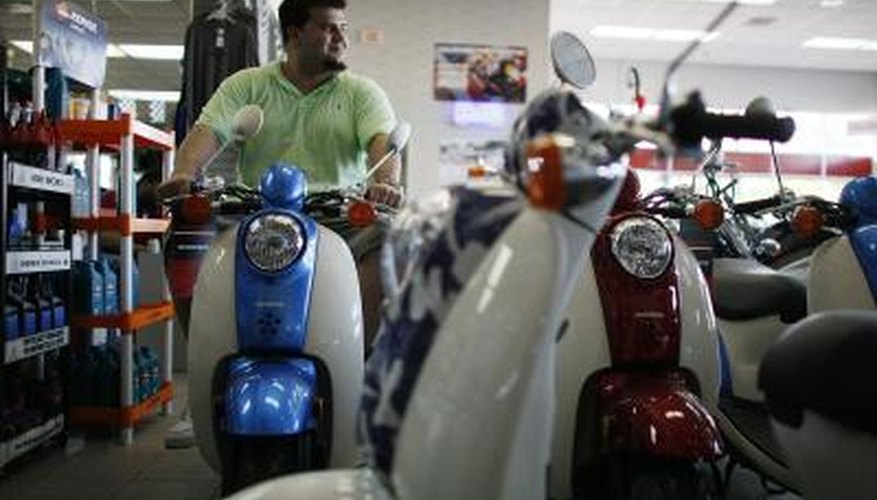 Photo Credit: Joe Raedle/Getty Images News/Getty Images Man looking at Honda scooters on showroom floor.