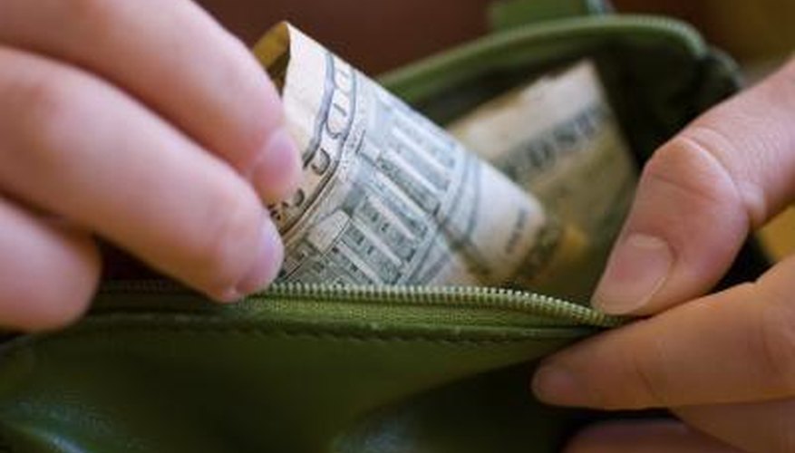 A close-up of a woman taking money out of her wallet.