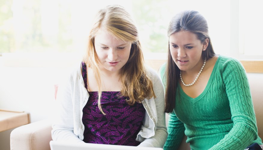 Two girls working on a laptop at home.